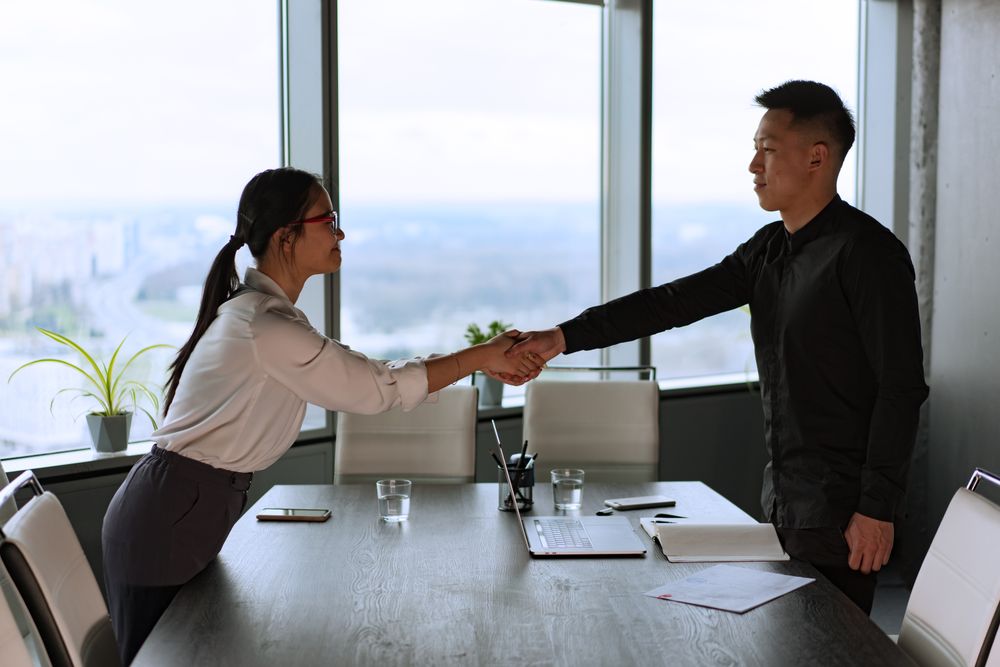 Poignée de main entre deux personnes autour d'une table de bureau